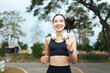 © PaeGAG - Young Asian woman running outdoors smiling with headphones