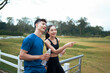 © PaeGAG - Young Asian couple enjoying outdoor walk pointing away