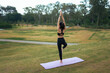 © PaeGAG - Woman practicing tree yoga pose on a mat outdoors