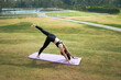 © PaeGAG - Woman practicing yoga outdoors in three legged downward dog pose