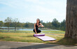 © PaeGAG - Young woman checking smartwatch preparing for outdoor yoga