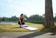 © PaeGAG - Asian woman rolling yoga mat checking smartwatch outdoors