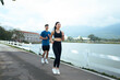 © PaeGAG - Smiling asian couple jogging outdoors by lake