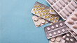 © Kateryna Zinenko  - Flat lay of assorted medical pills in blister packs, pharmaceutical tablets heap on blue background with copy space