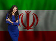 © millaf (Nemchinova) - Cheerful young woman in blue dress smiling against Iranian flag background