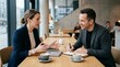 © Md Mujibur - Two professionals discuss charts over coffee in a modern cafe meeting, ideal for business consulting, teamwork, client planning, or workplace collaboration campaigns.