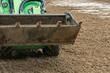 © kalyanby - Mini loader levelling quartz sand surface on equestrian arena outdoor horse riding ring footing installation and maintenance process