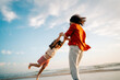 © Maria Sher/Stocksy - Child Plays at the Beach With Parent During Sunset