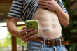 © Raymond Forbes LLC/Stocksy - Mobile phone App continuous glucose monitor home