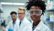 © Maryna - Three scientists in lab coats, safety goggles stand in brightly lit laboratory. Woman in foreground looks forward with determined expression. Part of research team working on scientific discovery,