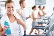 © peopleimages.com - Fitness, portrait and woman with bottle for treadmill, gym challenge or cardio workout. Happy, runner person and exercise machine with water beverage for pace practice, wellness or training in club