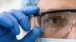 © iravgustin - Close up of a doctor in blue gloves adjusting protective surgical goggles and mask before a medical procedure.