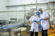 © Surachai - Two food industry professionals engaging in a conversation about quality assurance processes within a production environment
