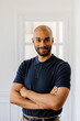 © BONNINSTUDIO/Stocksy - Man standing with crossed arms smiling confidently at camera