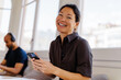 © BONNINSTUDIO/Stocksy - Brunette woman holding smartphone at office