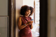© BONNINSTUDIO/Stocksy - Woman smiling while using smartphone on balcony