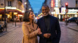 © Rendara Studio - Joyful mature multiracial couple walking and laughing along a lively evening city street