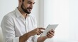 © Photos - Smiling man confidently engages with a sleek tablet in a bright minimalist workspace. AI Generated