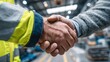 © Zarana  - Close-up of a warehouse handshake between two workers. Industrial partnership and business agreement concept.