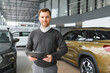 © Serhii - car seller standing in car salon and waiting for customers to come on sale
