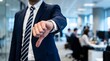 © Oye - Professional businessman in a navy suit making a negative thumbs down gesture while standing inside a modern corporate office environment