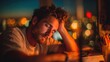 © Sergey - Exhausted young bearded man sitting at a desk with eyes closed, resting his head on his hand after a long day, warm evening indoor lighting, blurred