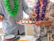 © luciano - Senior couple celebrating milestone 75th birthday, lighting candles on a festive cake, marking an important anniversary with happiness and leis at a cheerful party