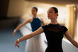 © Nikola Spasenoski - Ballet dancers practicing graceful arm positions and poised technique during a rehearsal in a bright dance studio with focused female dancer in foreground