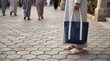 © ADF STUDIO - Muslim man holding a tote bag walking on a stone path