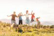 © Soloviova Liudmyla - Happy group of children and young person jumping holding hands in sunny summer mountain meadow during joyful outdoor activity enjoying beautiful golden hour light freedom and active lifestyle together