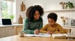 © Irfan - Supportive African American mother helps her young son with school homework in a bright modern kitchen, fostering education and bonding through home learning and focused study sessions at the table!