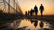 © Masque - Refugees attempting an illegal crossing along a border security fence at sunset.