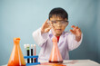 © Anisa - A curious young child wearing safety goggles and a lab coat observes a colorful chemistry experiment with laboratory glassware, promoting STEM education and scientific discovery.