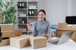 © David - Young asian woman entrepreneur working in her home office, managing inventory, preparing packages for shipment, and handling all aspects of her small business e commerce operations