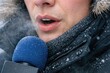 © Fotograf - A person holding a microphone standing in a snowy environment