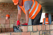 © SlavaStock - Specialist applies mortar to surface of brick wall. Builder prepares construction for improvement connecting components in work site