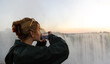 © Marc Romanelli - young woman photographing  at Victoria Falls at sunrise from the Zimbabwe side
