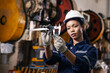 © kamonrat - Confident female manufacturing engineer performing precision quality inspection using a digital caliper to measure a machined metal component in an industrial factory.