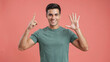 © Aminograpix - Smiling Young Man Counting with Fingers on Coral Studio Background