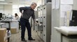 © Xenia - Senior Asian office clerk holding his aching lower back near a filing cabinet. Elderly businessman suffering from back pain and stress at the workplace