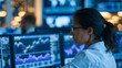 © Laura - Faceless female financial analyst examining stock market charts on multiple monitors in a trading room, data-driven investment decision-making, defocused trading screens in