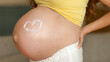 © Home-stock - Closeup of pregnant belly with heart shape drawn in moisturizer cream