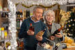 © JackF - Elderly husband and wife choosing wine and whiskey for Christmas celebration at supermarket