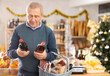© JackF - Elderly man buyer chooses bottle of whiskey in christmas decorated grocery store