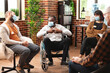 © DC Studio - Wheelchair user shares problems with therapy group, illustrating health safety, counseling support and recovery discussion inside a supportive therapy room.