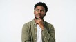 © Creative experience  - A young black man wearing a green shirt looking up and thinking with his hand on his chin against a plain background
