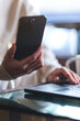 © Farknot Architect - Vertical closeup image of a woman using smart phone and laptop computer in cafe
