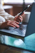 © Farknot Architect - Vertical closeup image of a woman using smart phone and laptop computer in cafe