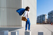 © Westend61 - Smiling businessman holding blazer on shoulder standing with shoulder bag on concrete block