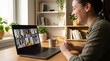 © CH - Young professional woman attending virtual team meeting on laptop. Remote worker smiling during online video conference call at home office.